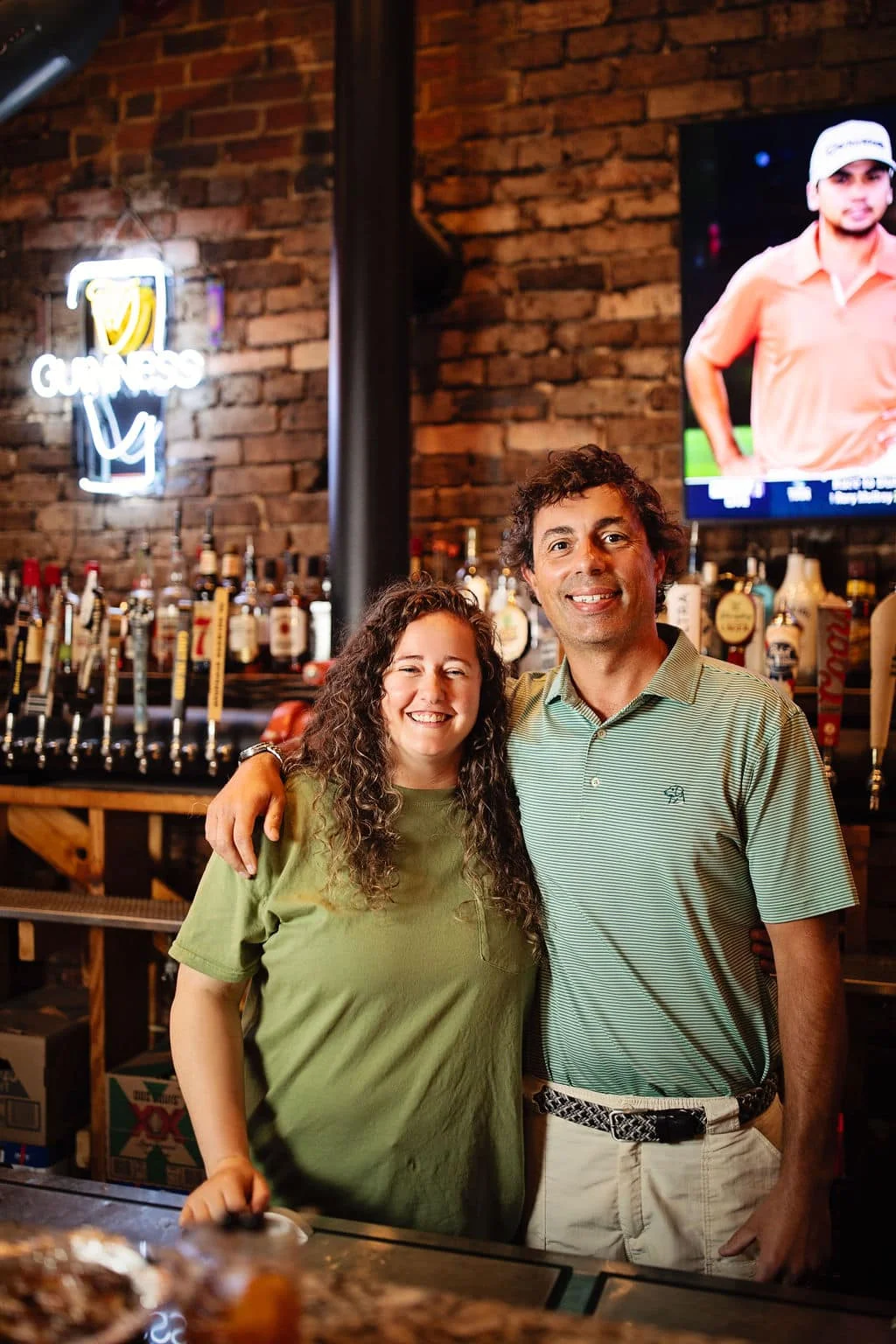 Friendly bartenders posing in a cozy bar with exposed brick