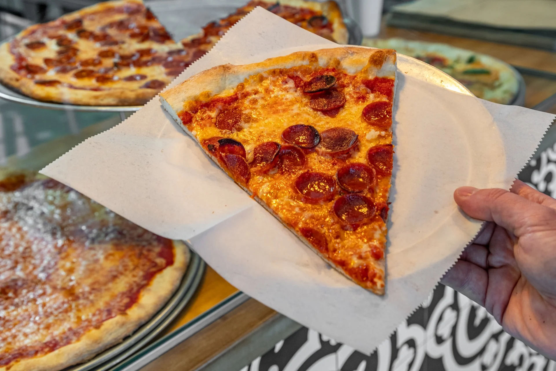 Slice of pepperoni pizza served on a paper plate