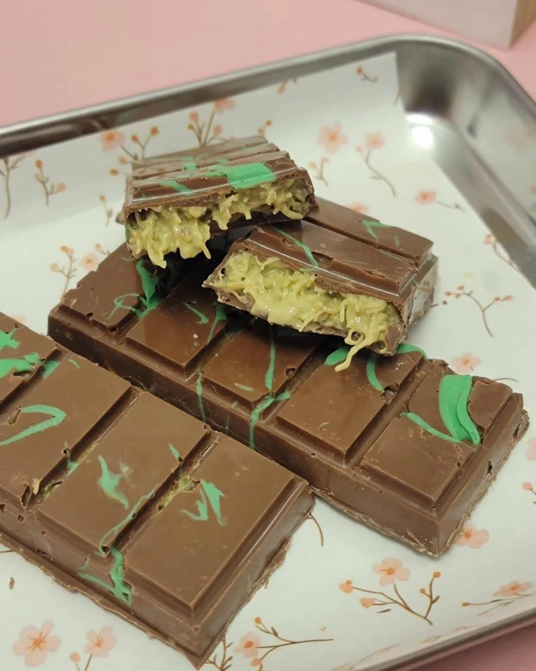 Chocolate bars on a tray, with one bar cut open to show a creamy, coconut-like filling inside.