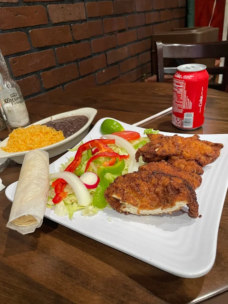 A traditional Milanesa de Pollo platter from El Ranchito Poblano, featuring a breaded chicken cutlet served with salad, a tortilla, rice, and beans.