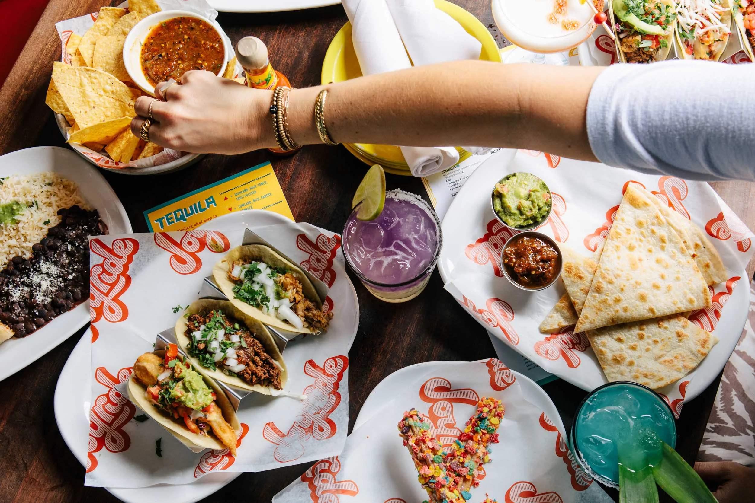 Colorful Mexican tacos with sides and drinks on a wooden table