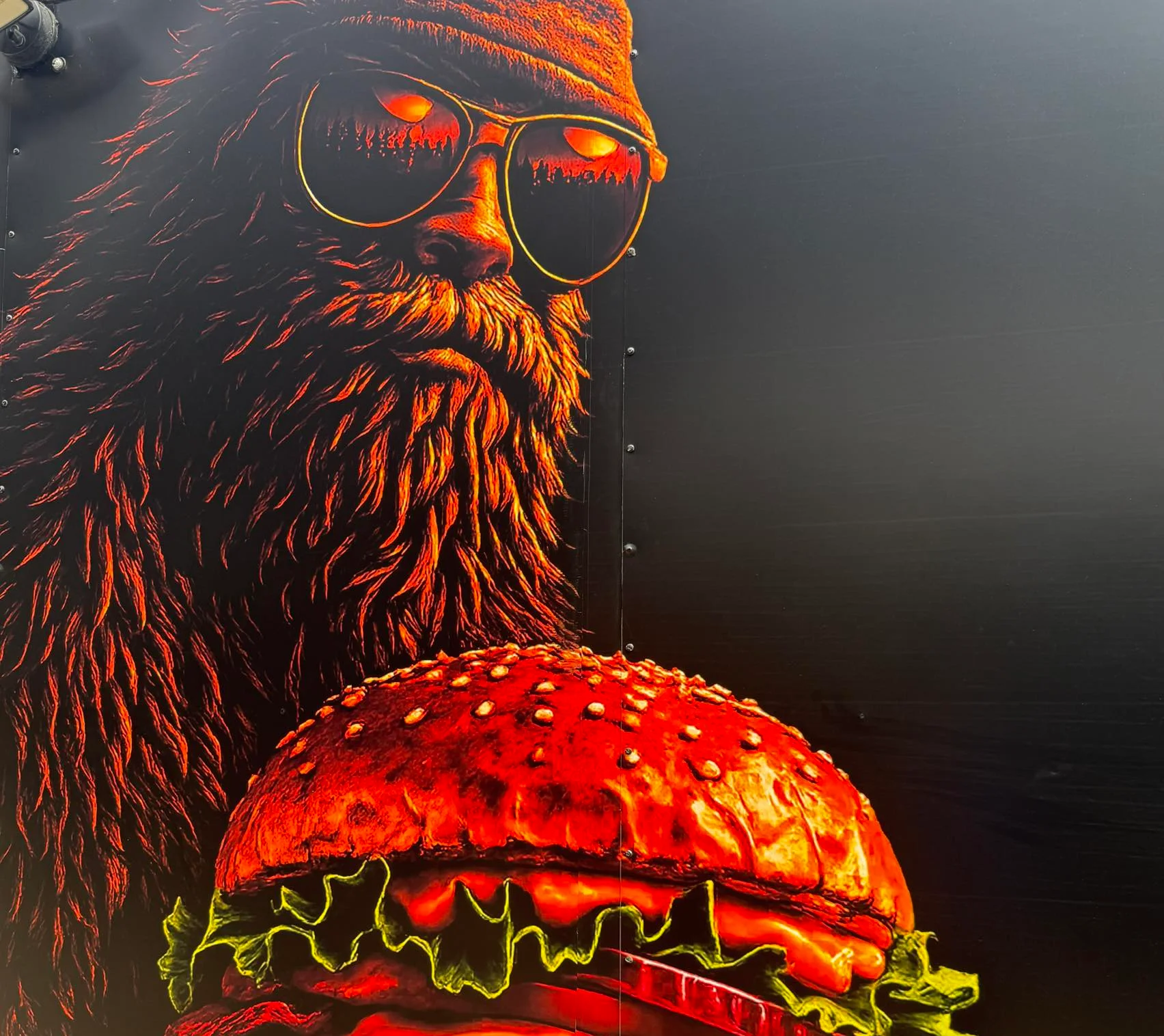 Vibrant mural of a bearded man holding a dripping burger.