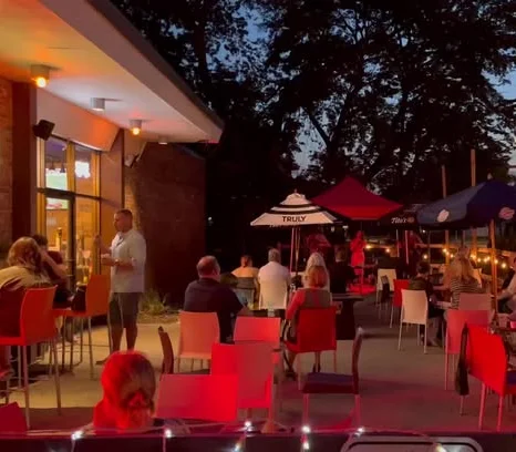 Outdoor dining area at dusk with colorful chairs and umbrellas