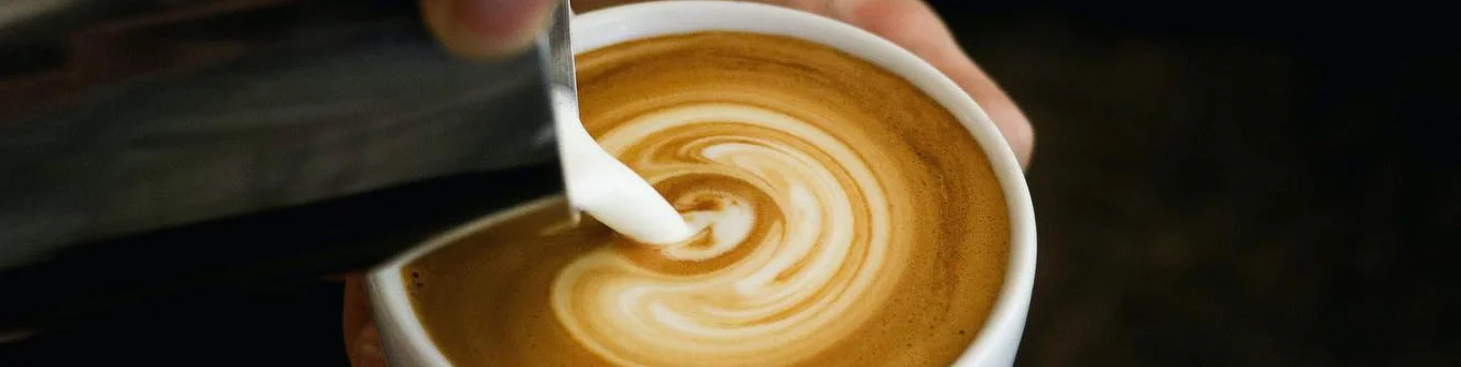 Barista pouring latte art into a cup of coffee