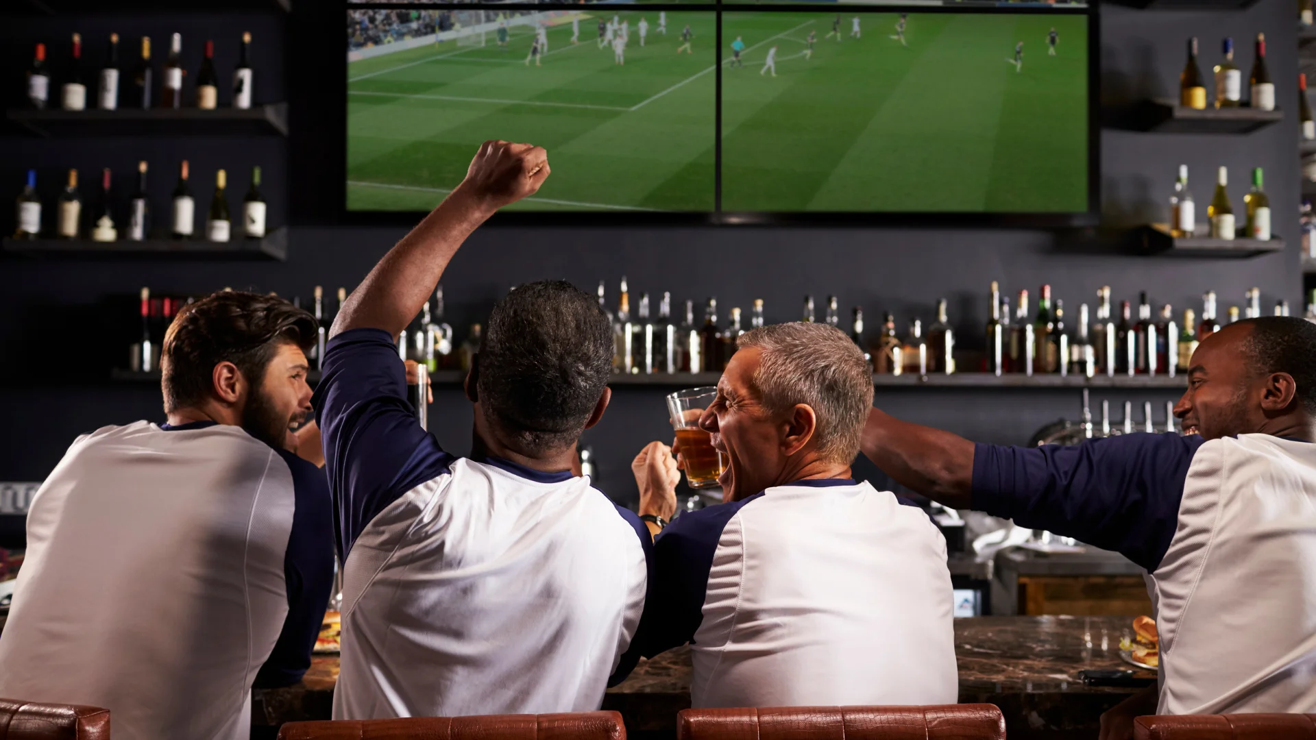 Friends cheering while watching a soccer game at a bar
