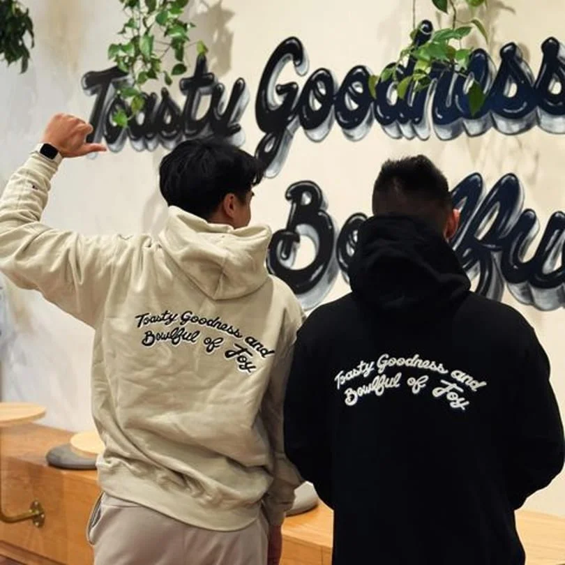Two friends in hoodies showcasing restaurant branding