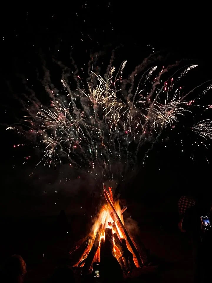 Bonfire with fireworks lighting up the night sky