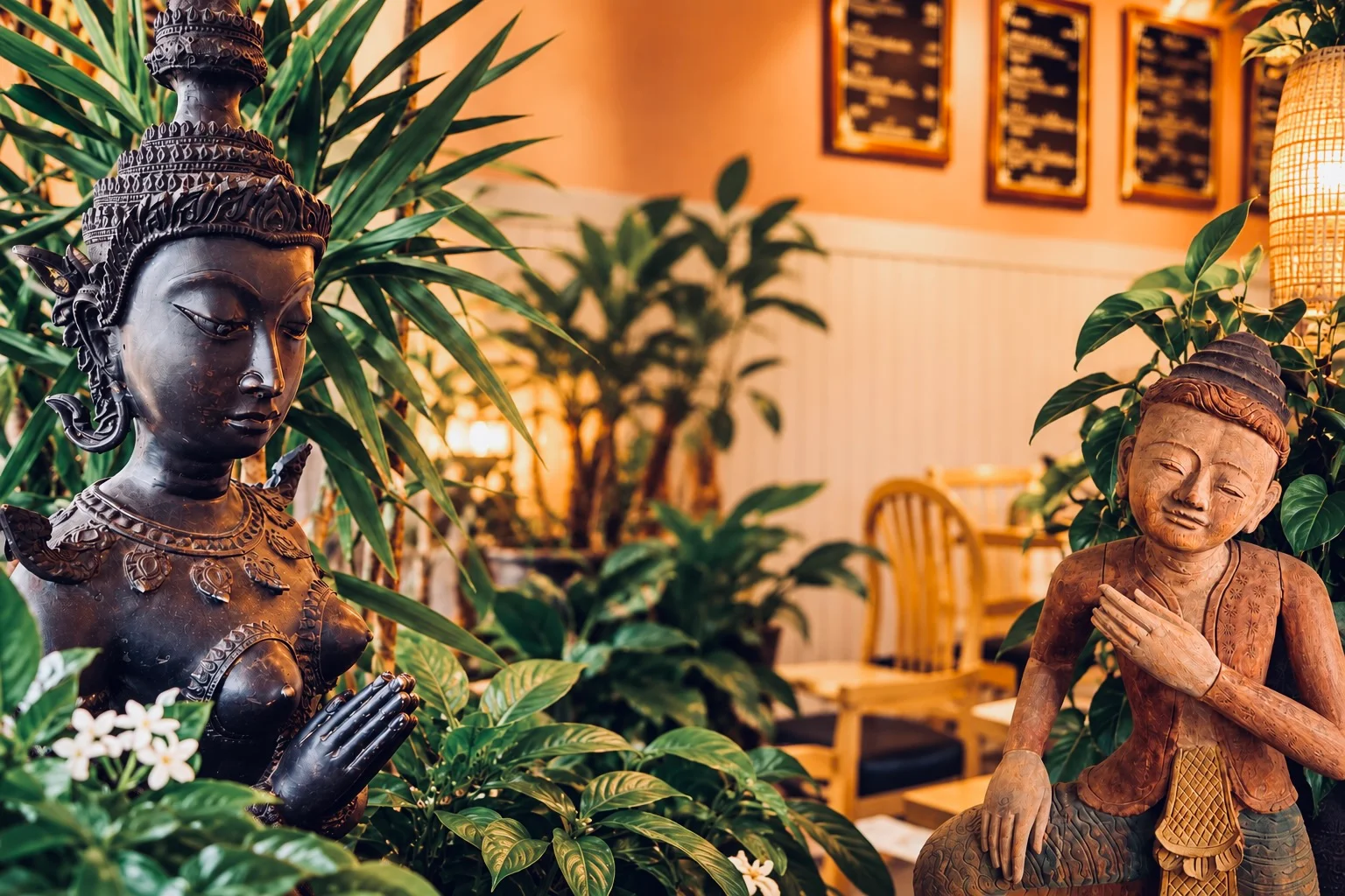 Restaurant dining room with white tablecloths, tropical plants, and warm lighting