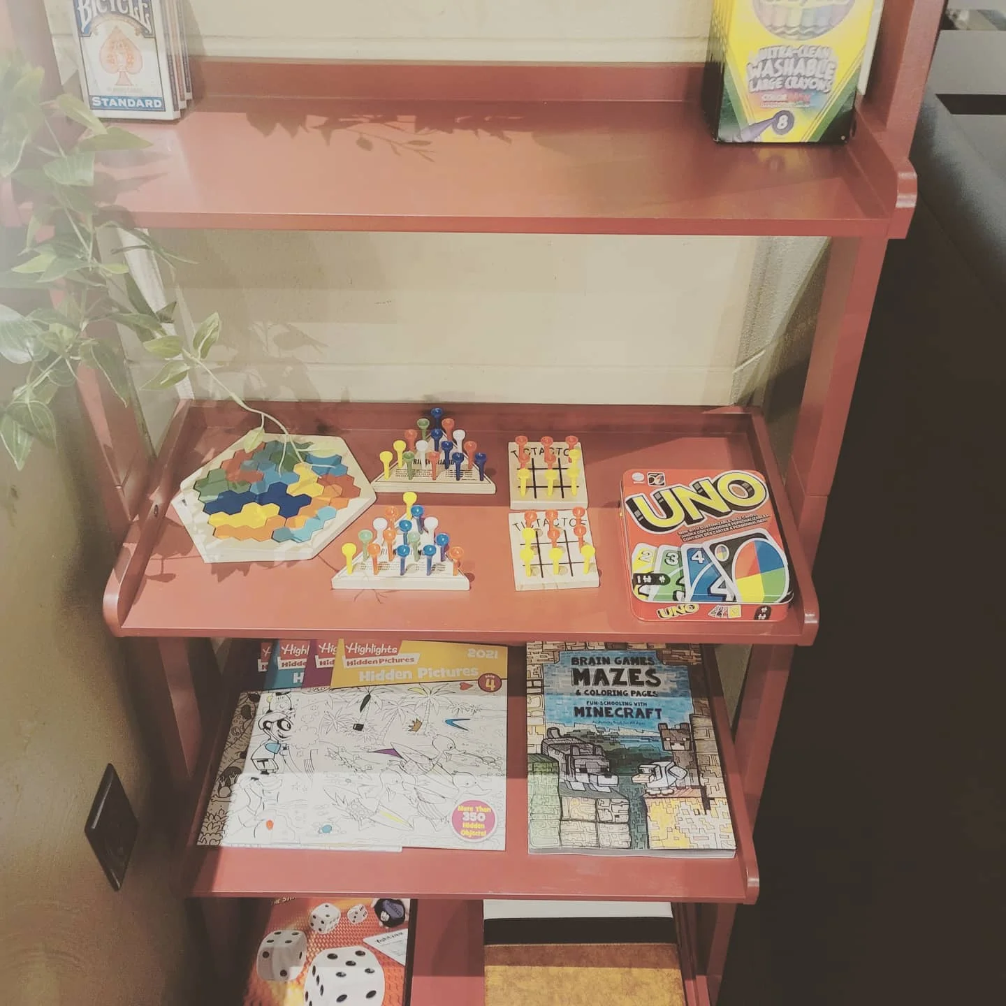 Colorful board games and puzzles on a red shelf