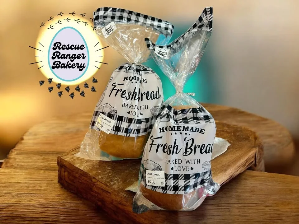 Two bags of freshly baked bread with a homemade label, placed on a wooden surface.