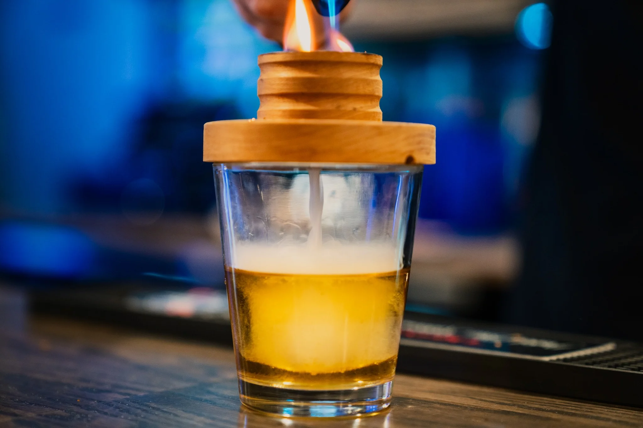 Bartender igniting a cocktail with a wooden lid