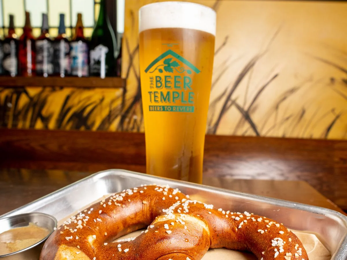 Soft pretzel served with mustard in a cozy bar setting