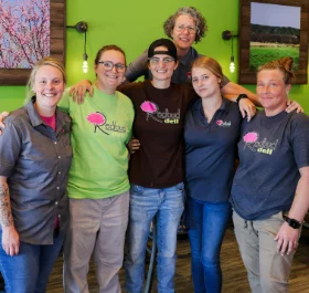 Friendly staff posing together in a vibrant deli interior
