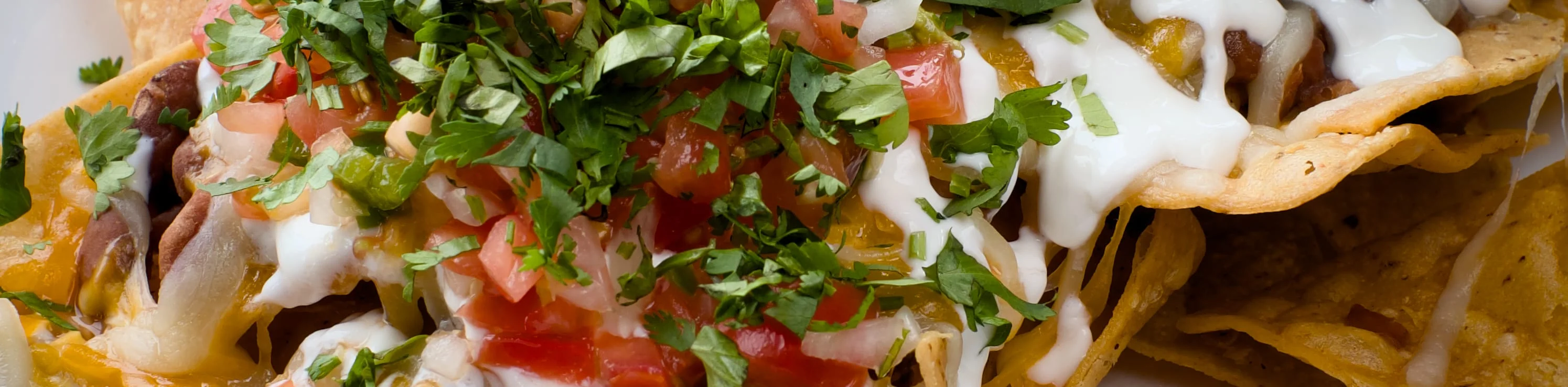 Loaded nachos topped with guacamole and fresh herbs