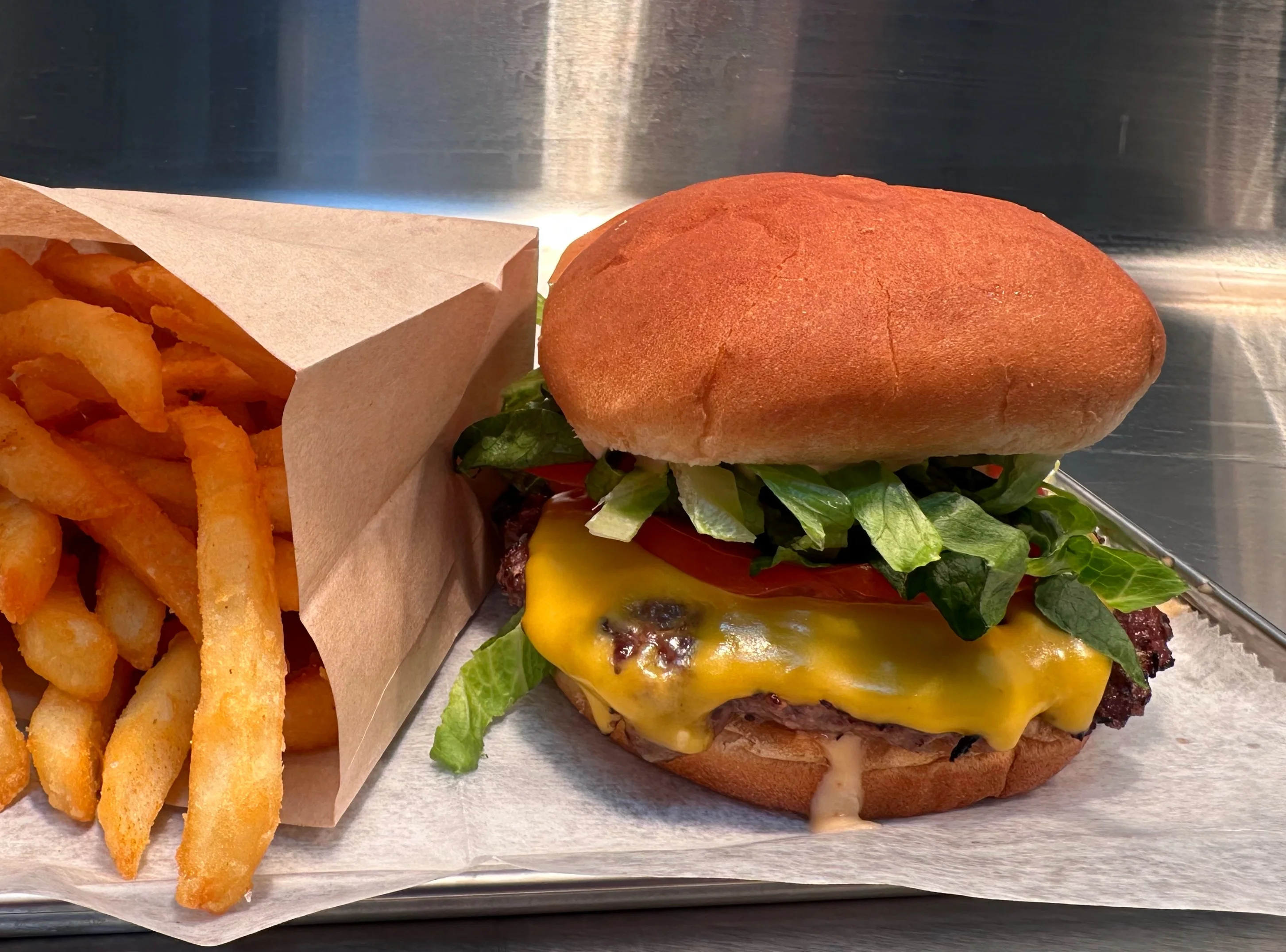 A cheeseburger with lettuce and tomato next to a serving of fries.