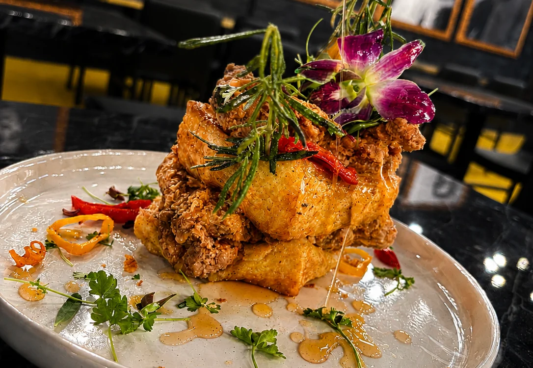 A beautifully plated fried chicken dish garnished with herbs and flowers.