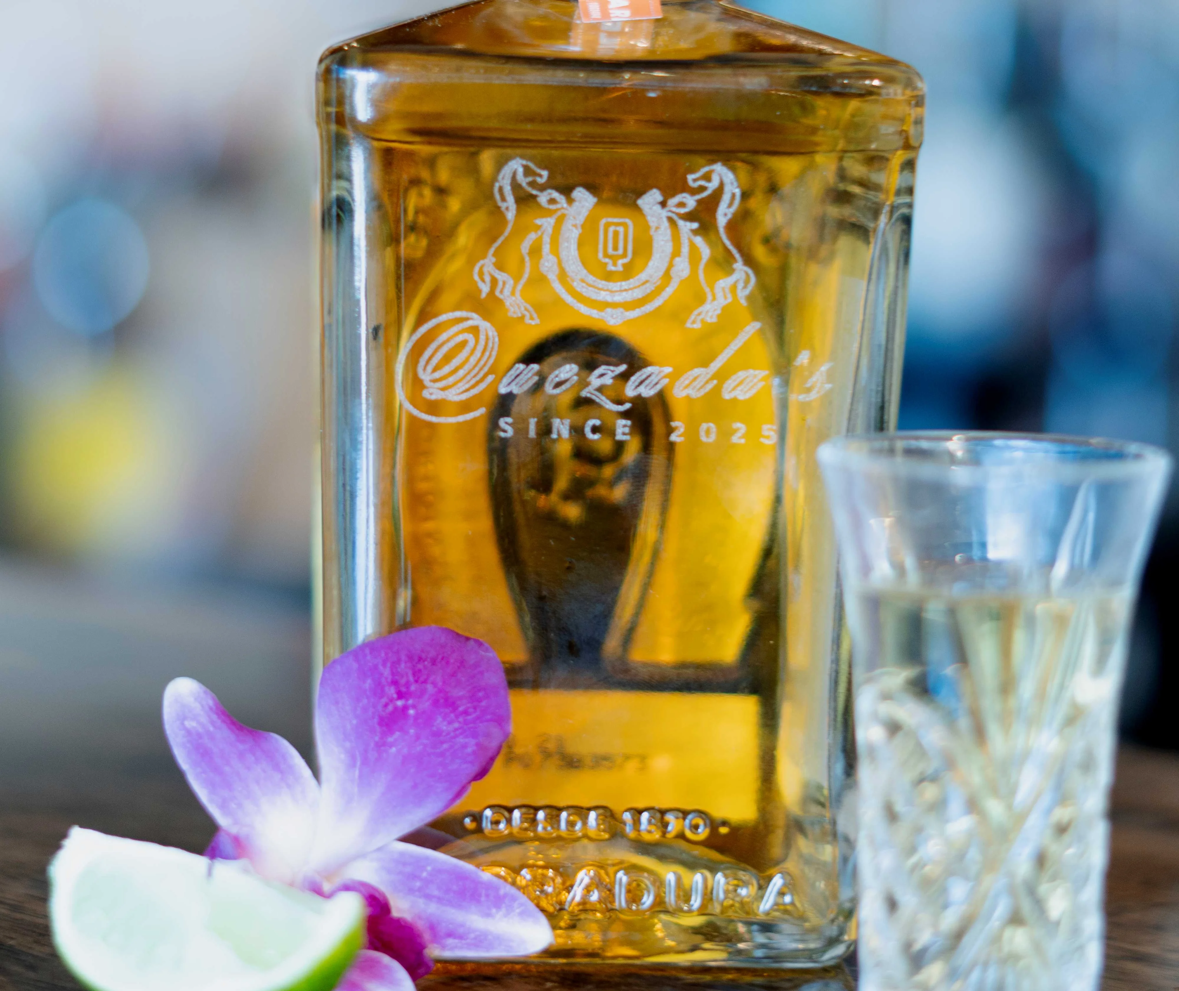 Bottle of reposado tequila with lime and orchid garnish