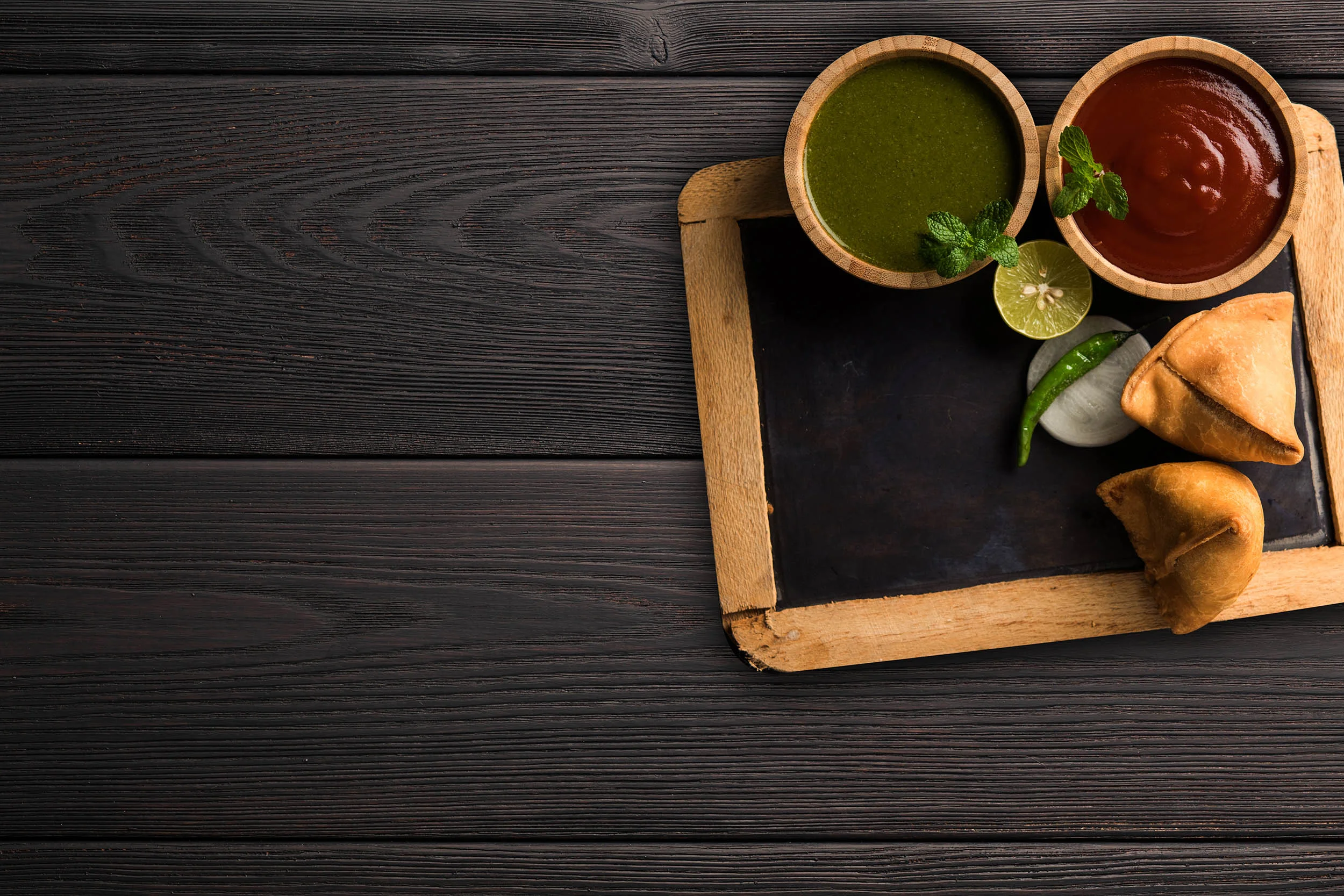 Plate of samosas with mint and tamarind chutneys
