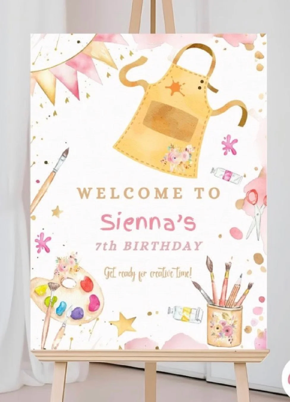 A colorful birthday welcome sign featuring an artist's apron, brushes, and craft supplies, indicating a creative birthday party theme.