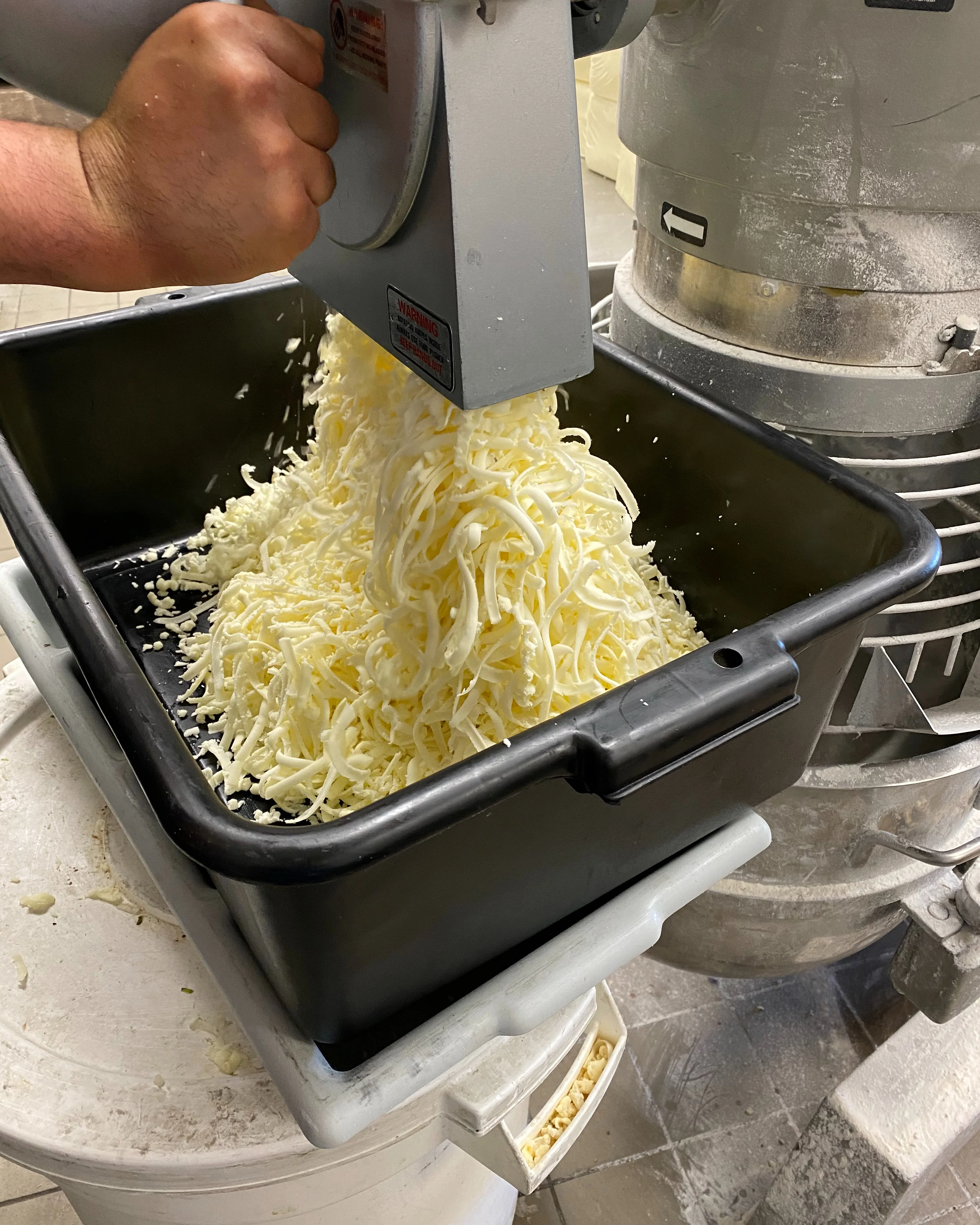 Freshly shredded mozzarella cheese in a commercial kitchen