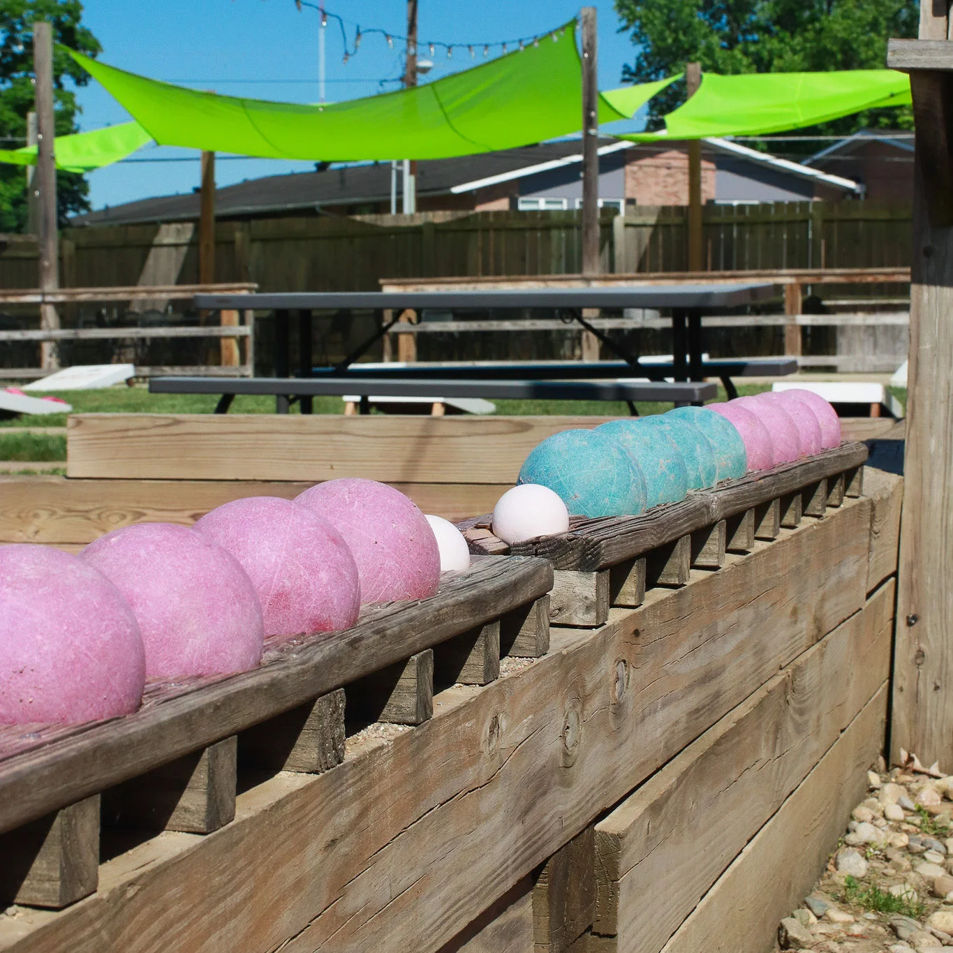 Colorful outdoor game area with bowling balls and green canopies