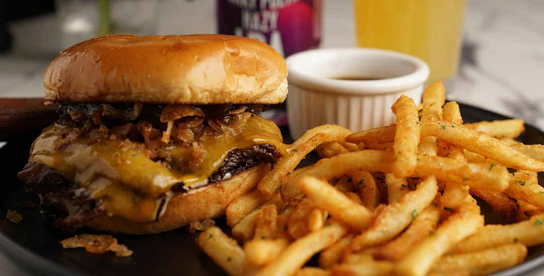 Juicy cheeseburger with crispy fries on a black plate