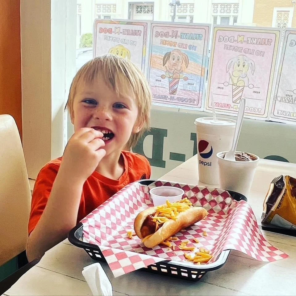 Child enjoying a chili cheese dog in a casual dining setting
