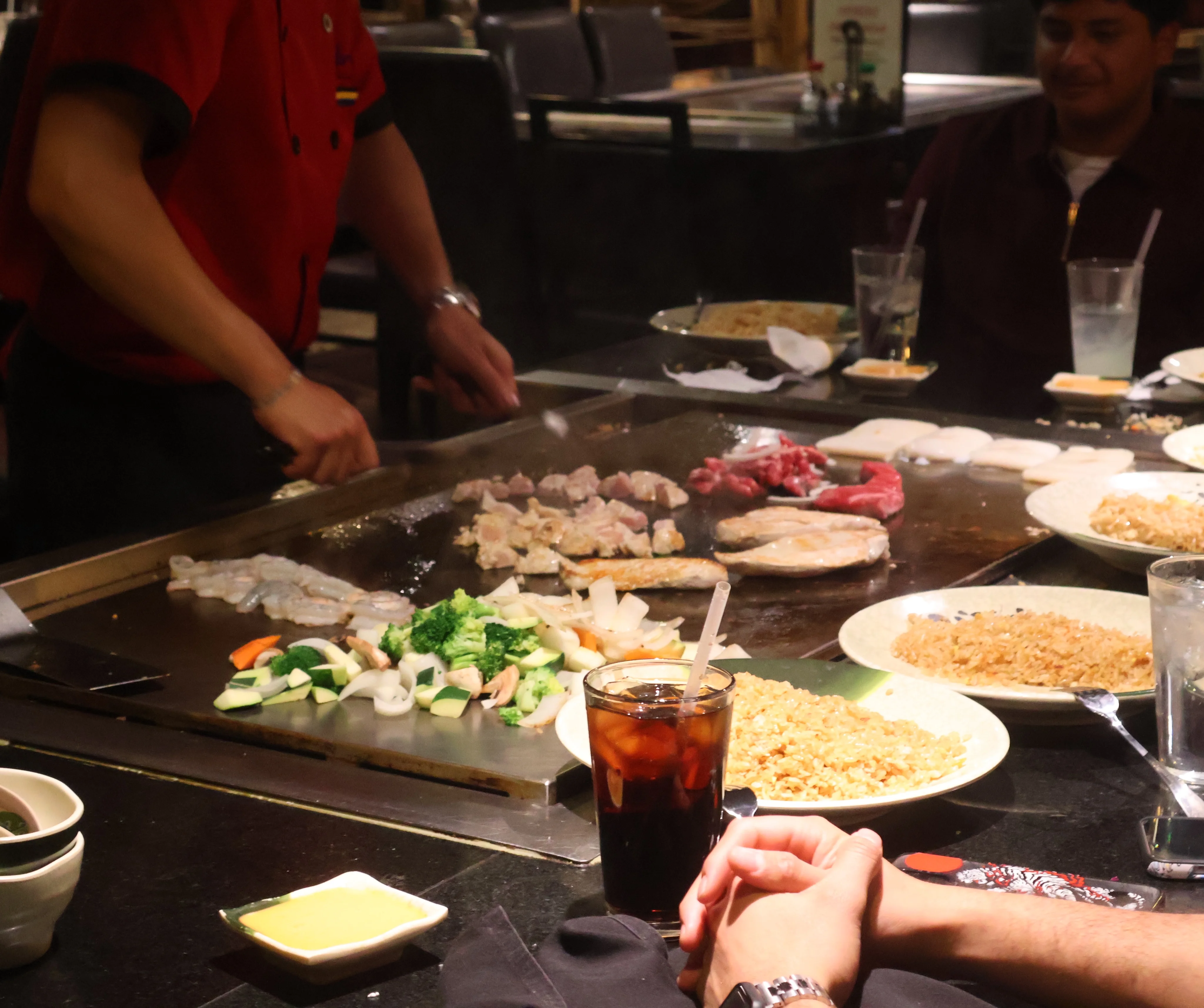 Teppanyaki grill with assorted meats and vegetables being prepared