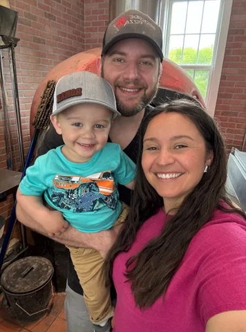A happy family selfie with a child in a restaurant setting.
