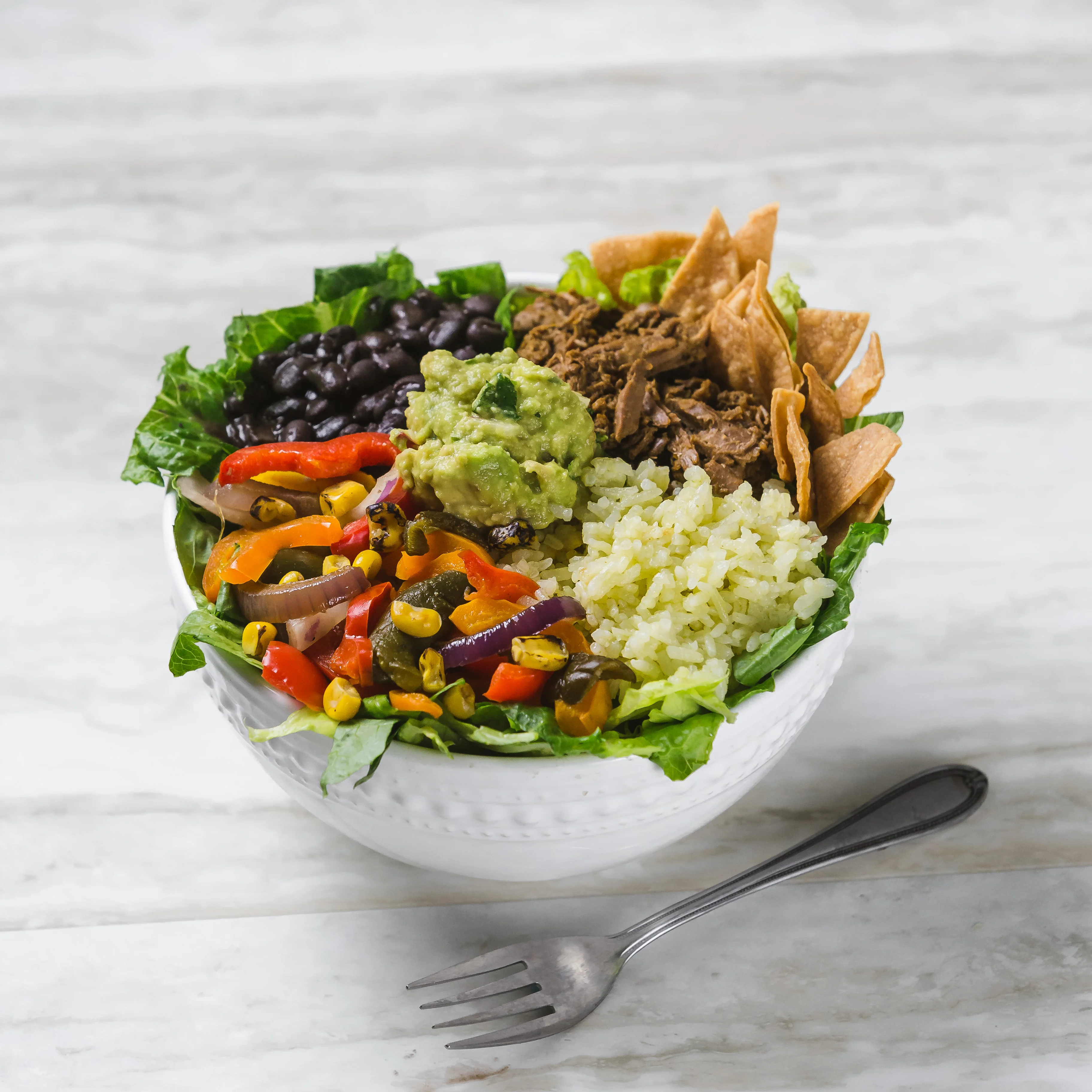 Colorful Mexican burrito bowl with guacamole and black beans