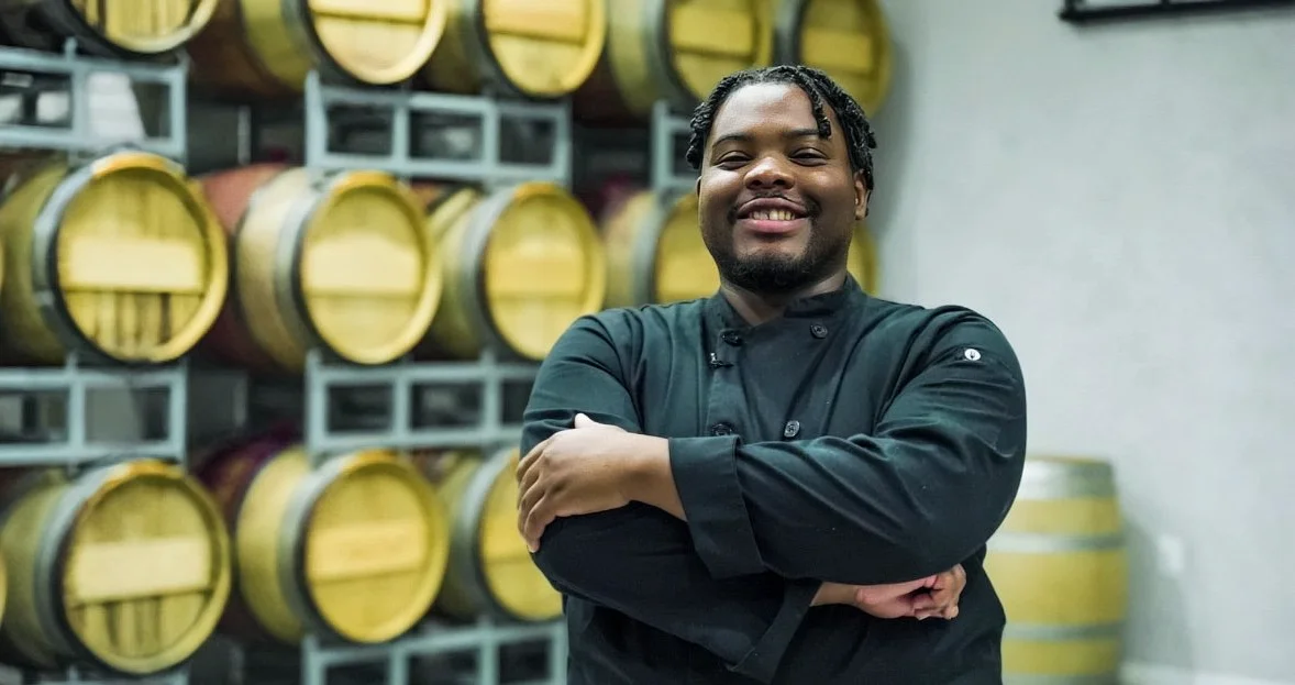 Chef smiling in front of wine barrels in a restaurant