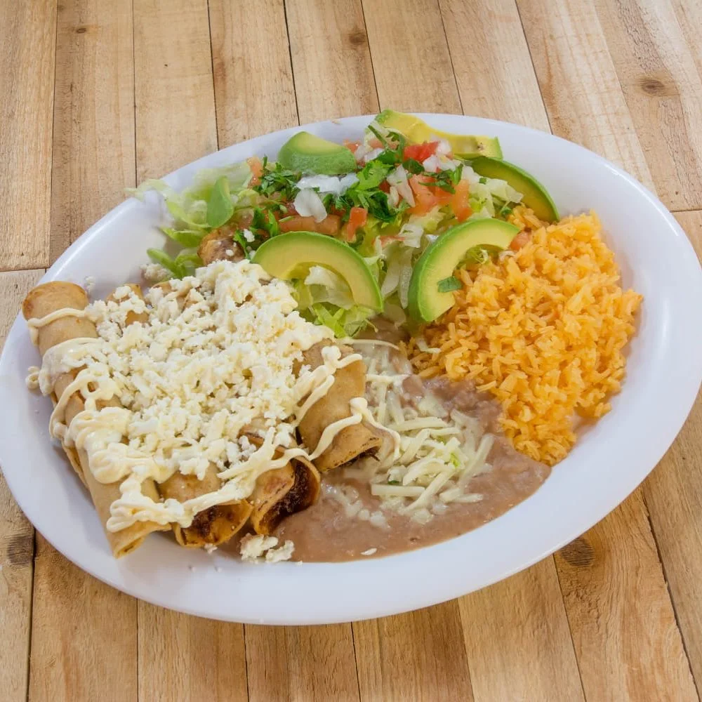 Plate of Mexican flautas with rice and fresh toppings