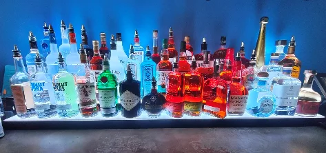 Colorful array of spirits displayed on a backlit bar shelf