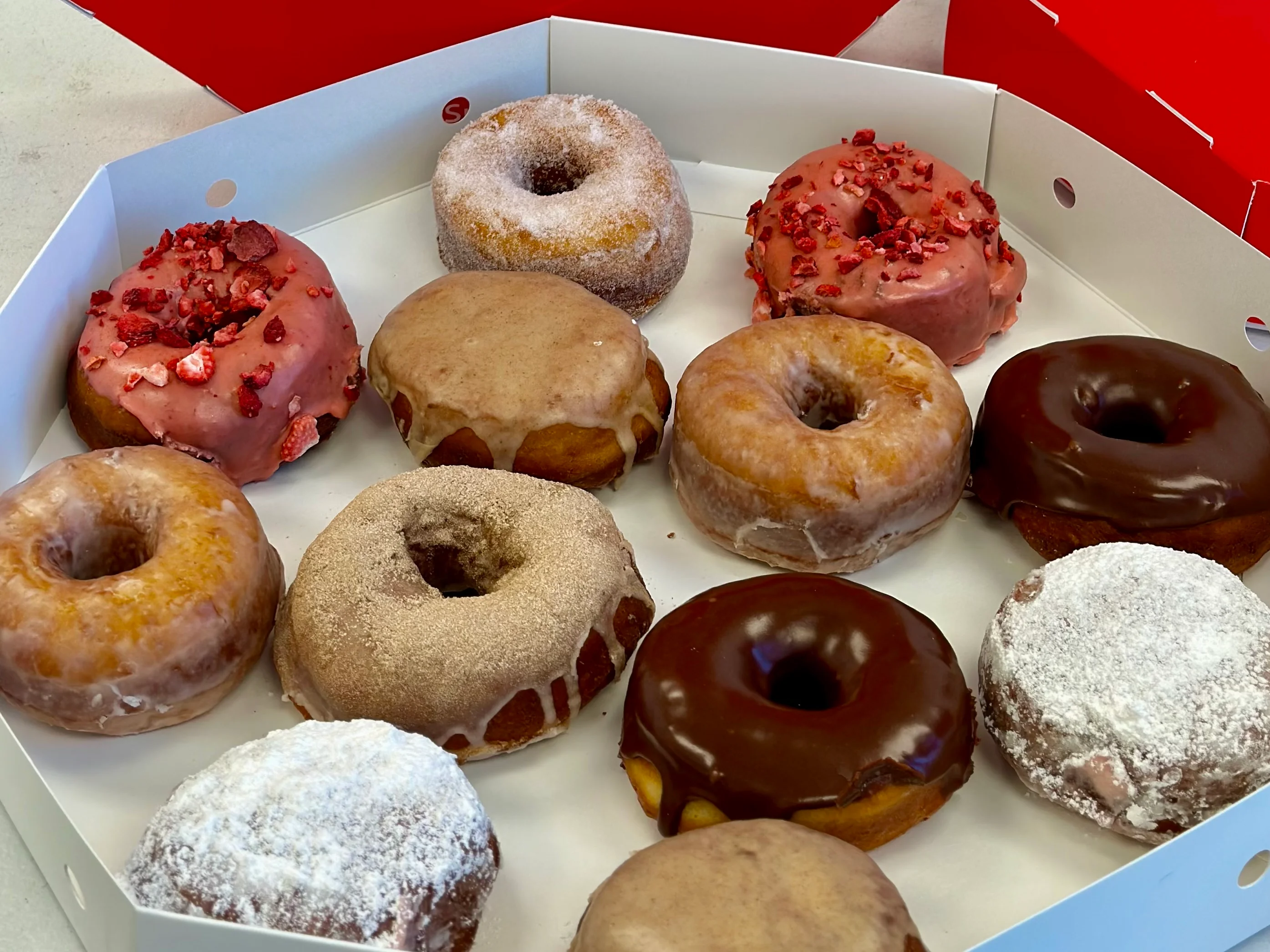 Assorted gourmet donuts in a bakery box