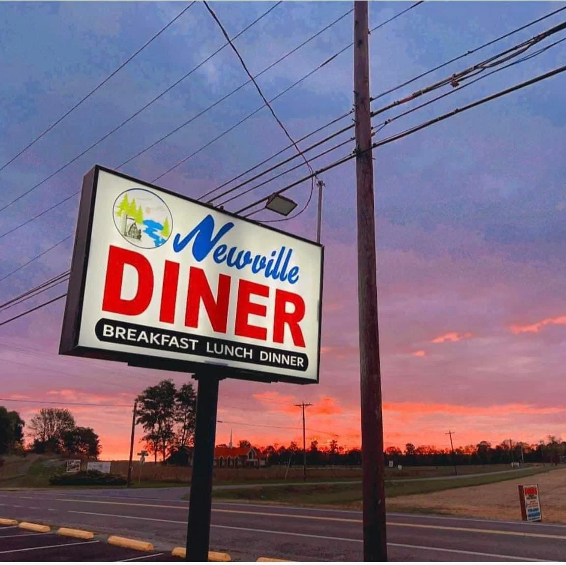 Newville Diner sign at sunset, showcasing breakfast, lunch, and dinner options