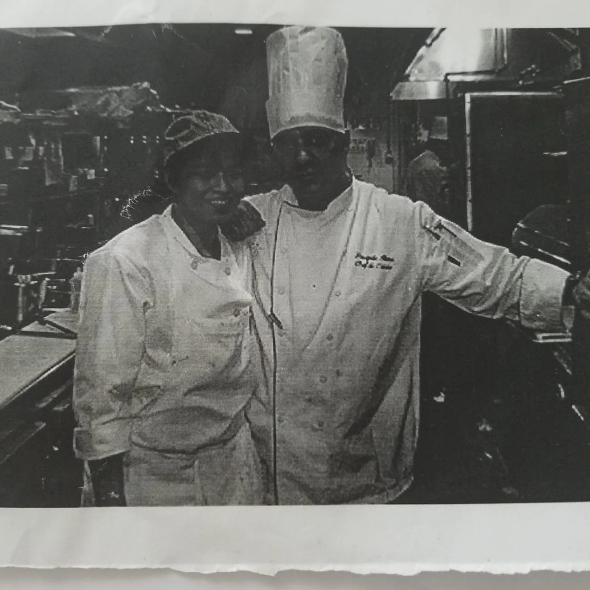 Chefs posing together in a bustling restaurant kitchen