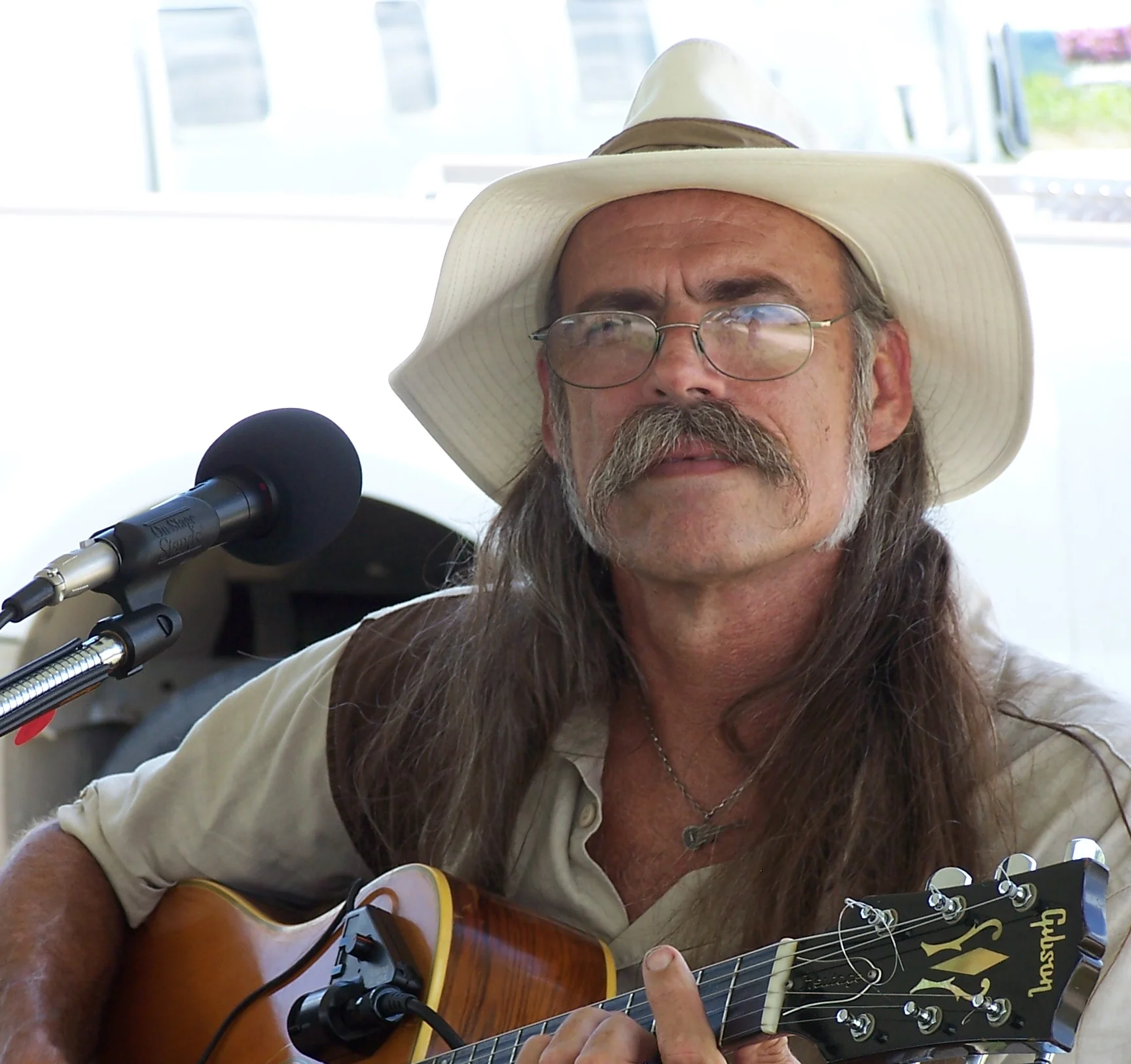 Musician playing acoustic guitar at an outdoor event