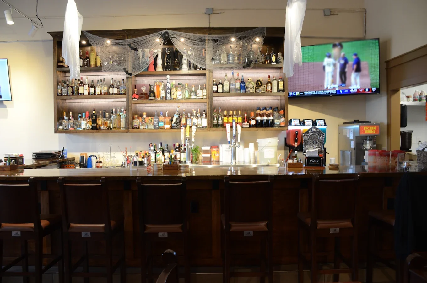 Modern bar counter with a variety of spirits and a TV showing a sports game