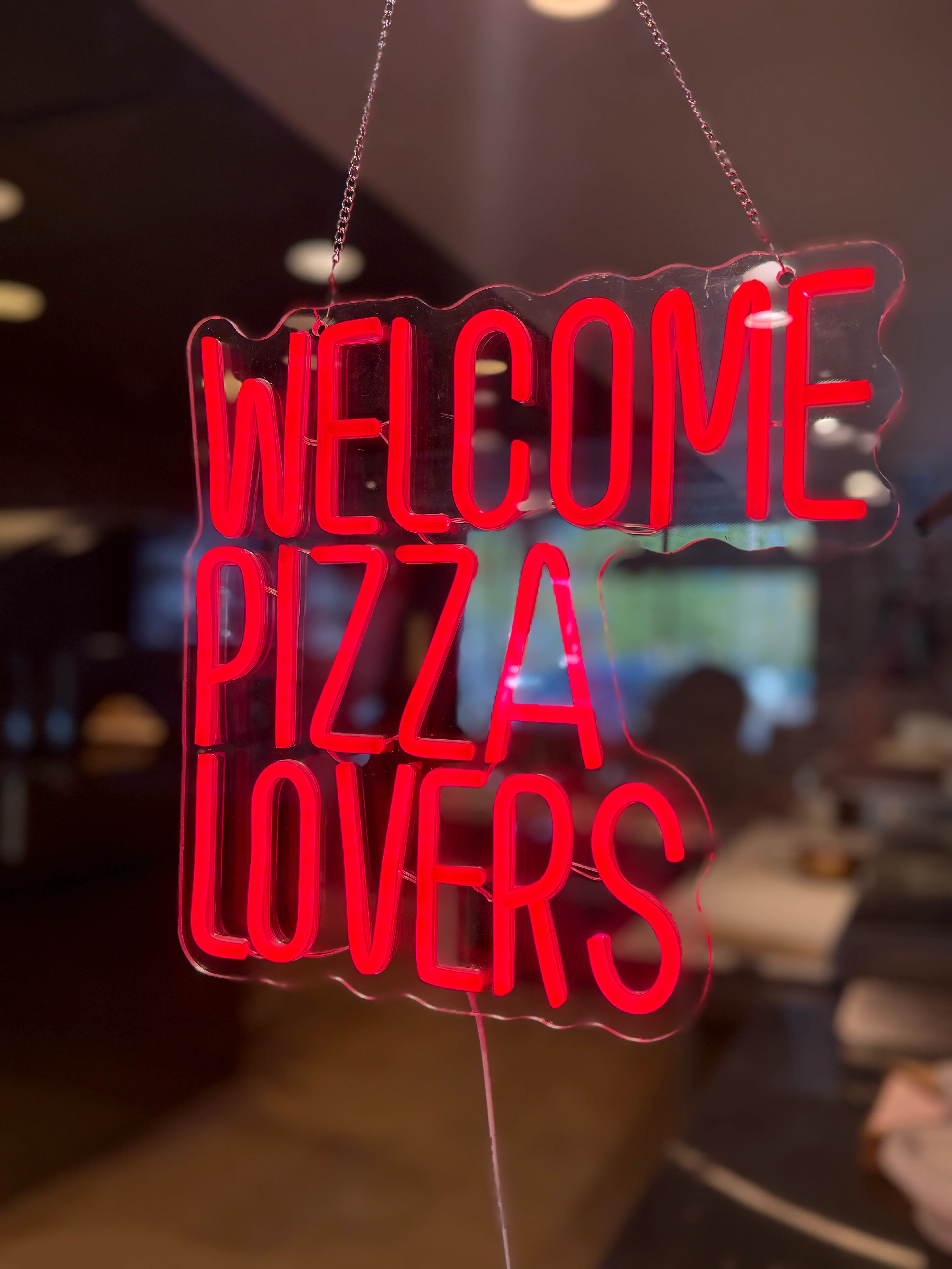 Neon sign welcoming pizza lovers to a cozy restaurant