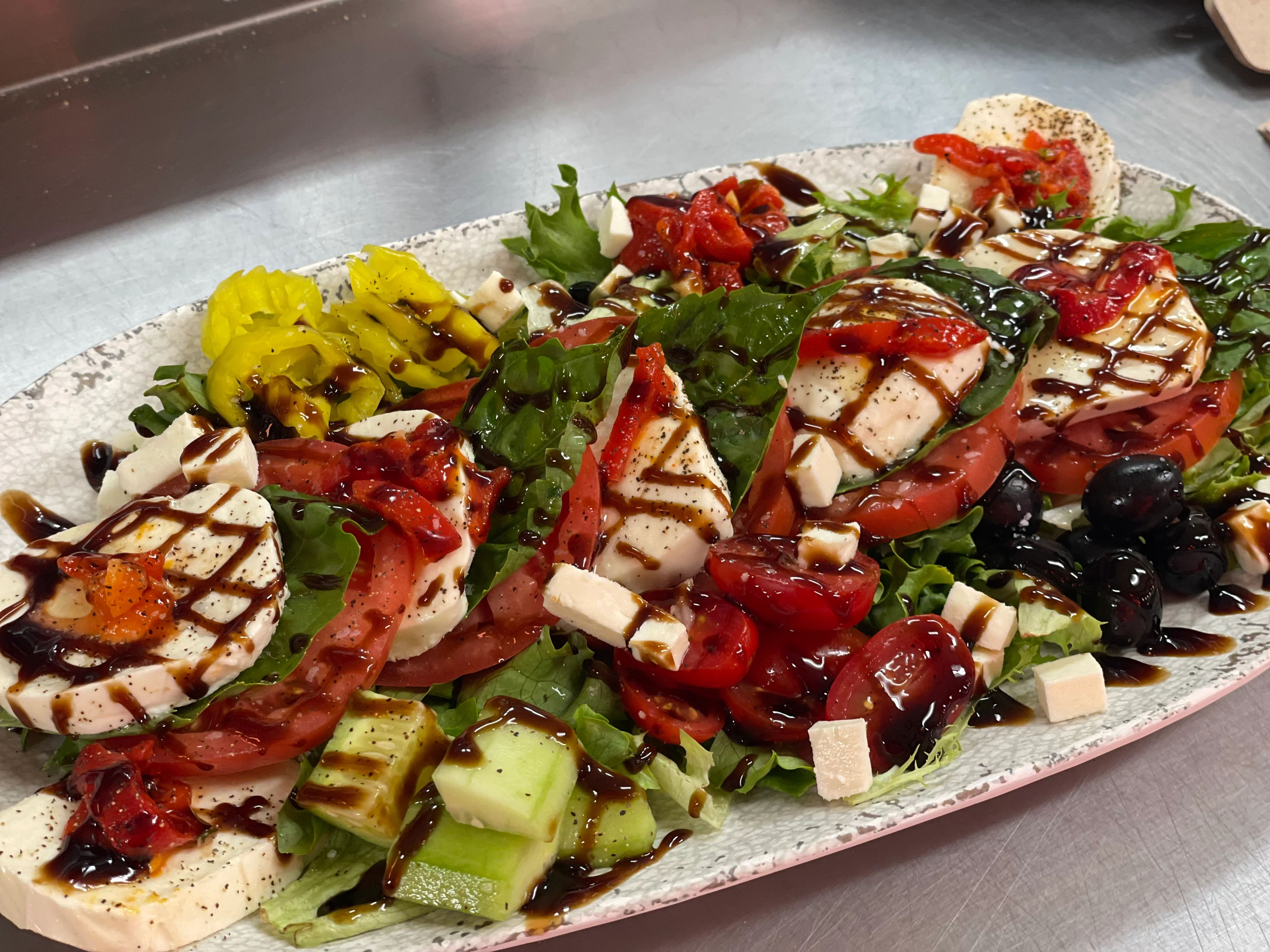 Rustic Italian caprese spread with fresh bread, cherry tomatoes, cheese, salami, pesto, potatoes, and red wine, ideal for a traditional Italian dining experience at Nina's Pizzeria in Chittenango, NY
