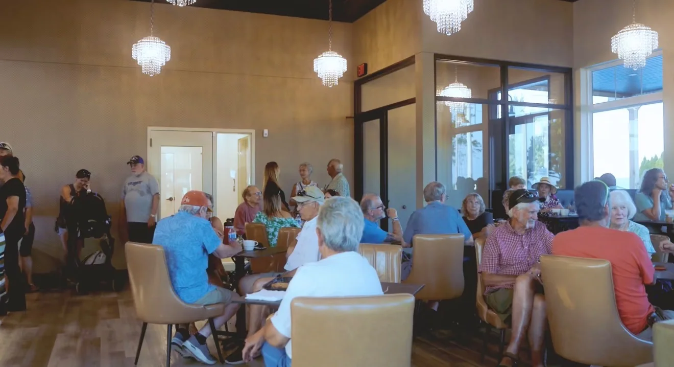 Busy restaurant dining room with crystal chandeliers and guests