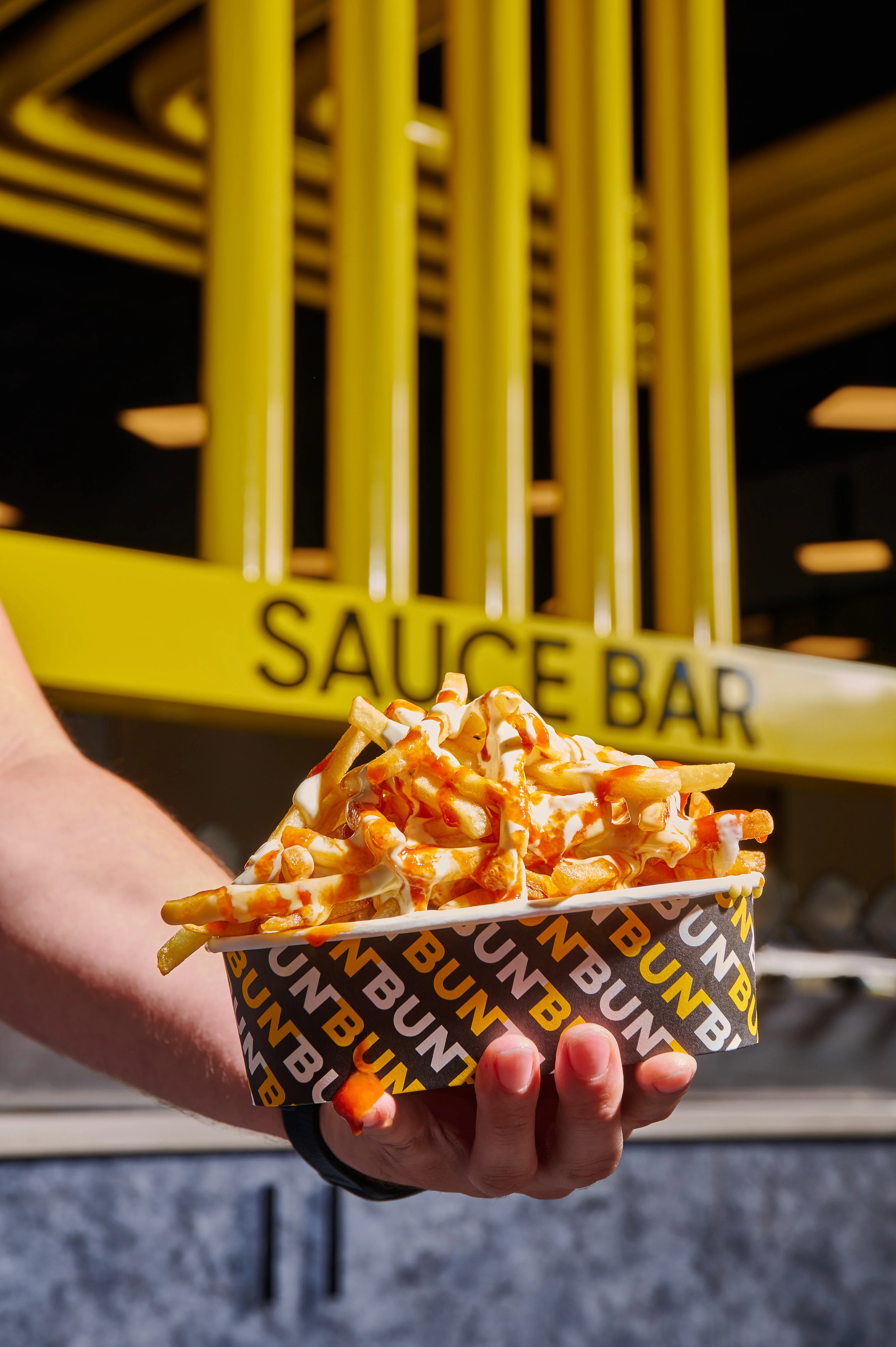 Loaded fries drizzled with sauce in a vibrant restaurant setting
