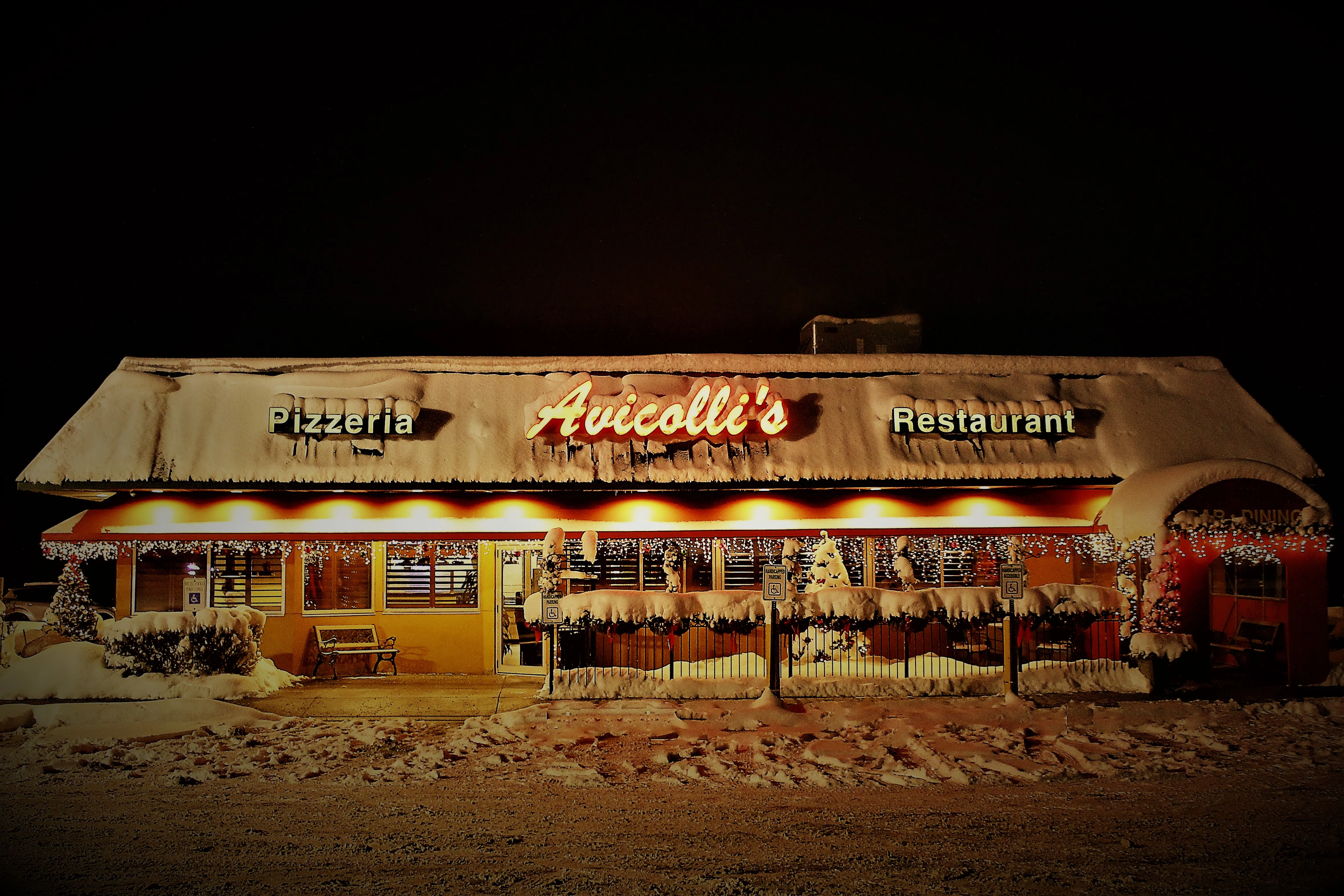 Charming pizzeria exterior adorned with snow and festive lights