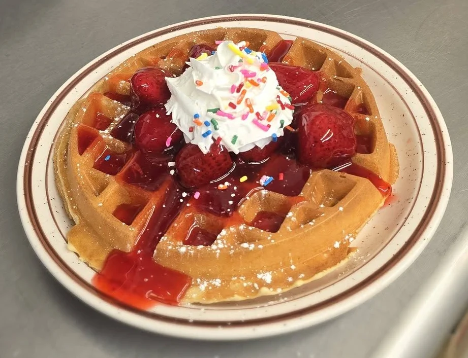 Delicious Belgian waffle topped with strawberries and whipped cream