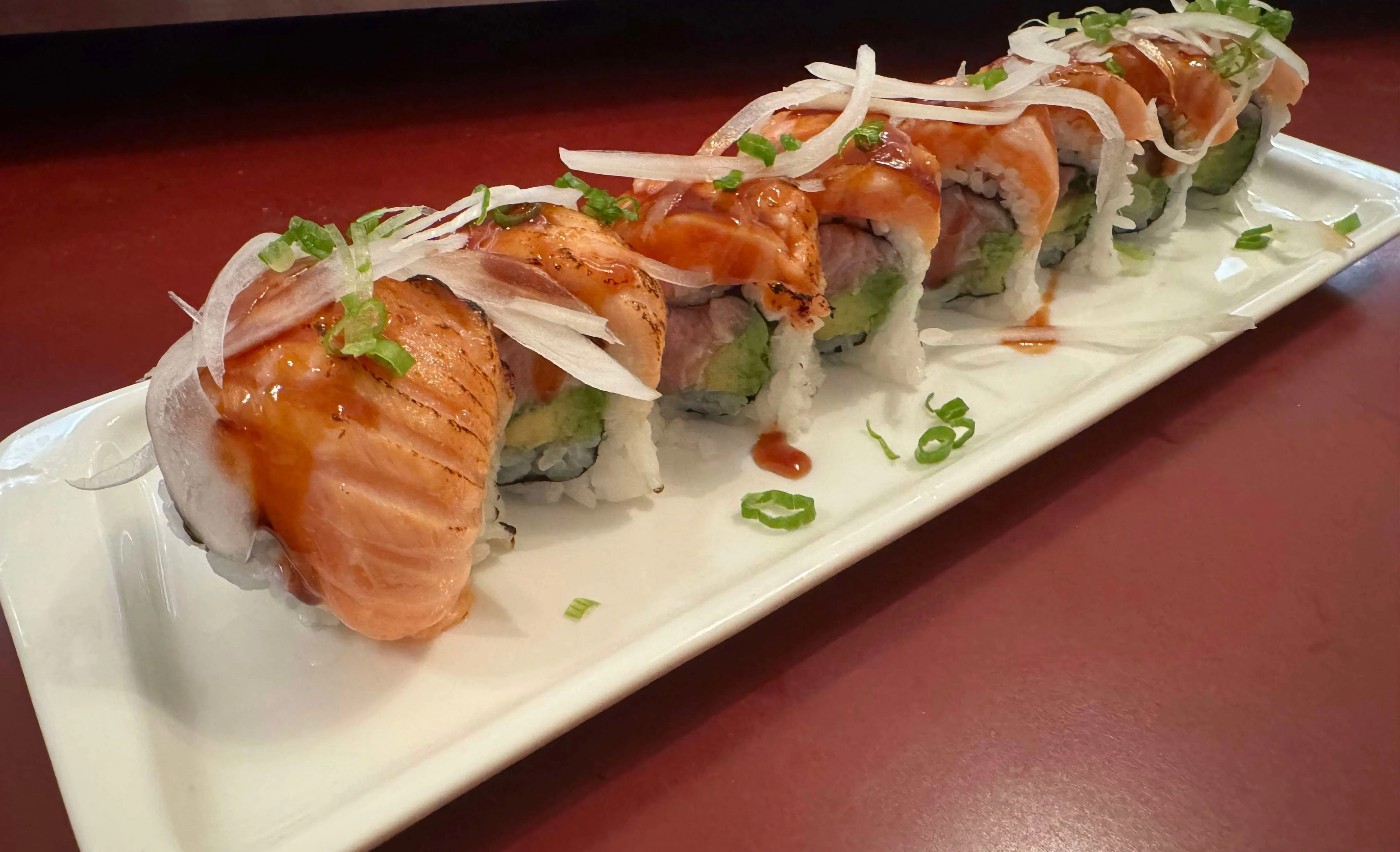 Japanese sushi roll with salmon and avocado on a white plate
