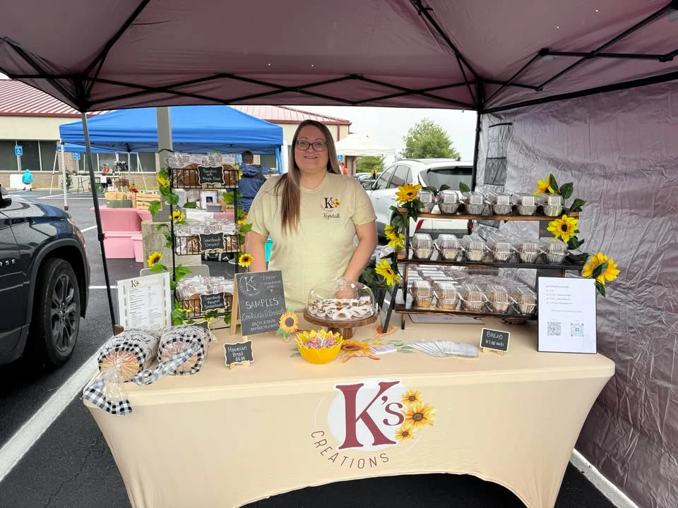 A vendor stall featuring an array of baked goods, including loaves and cookies, set up at an outdoor market.