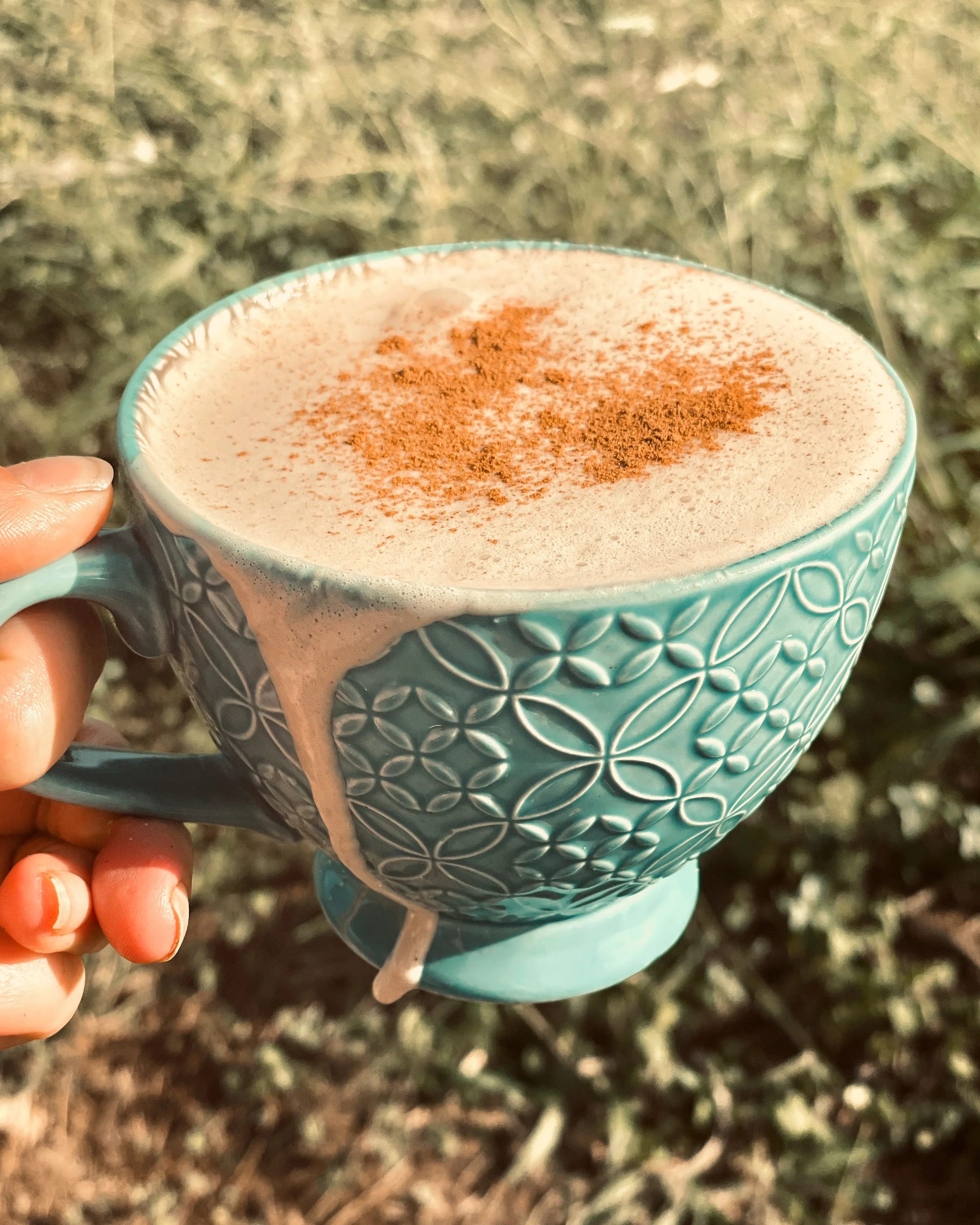 Chai latte topped with cinnamon in a decorative teal cup
