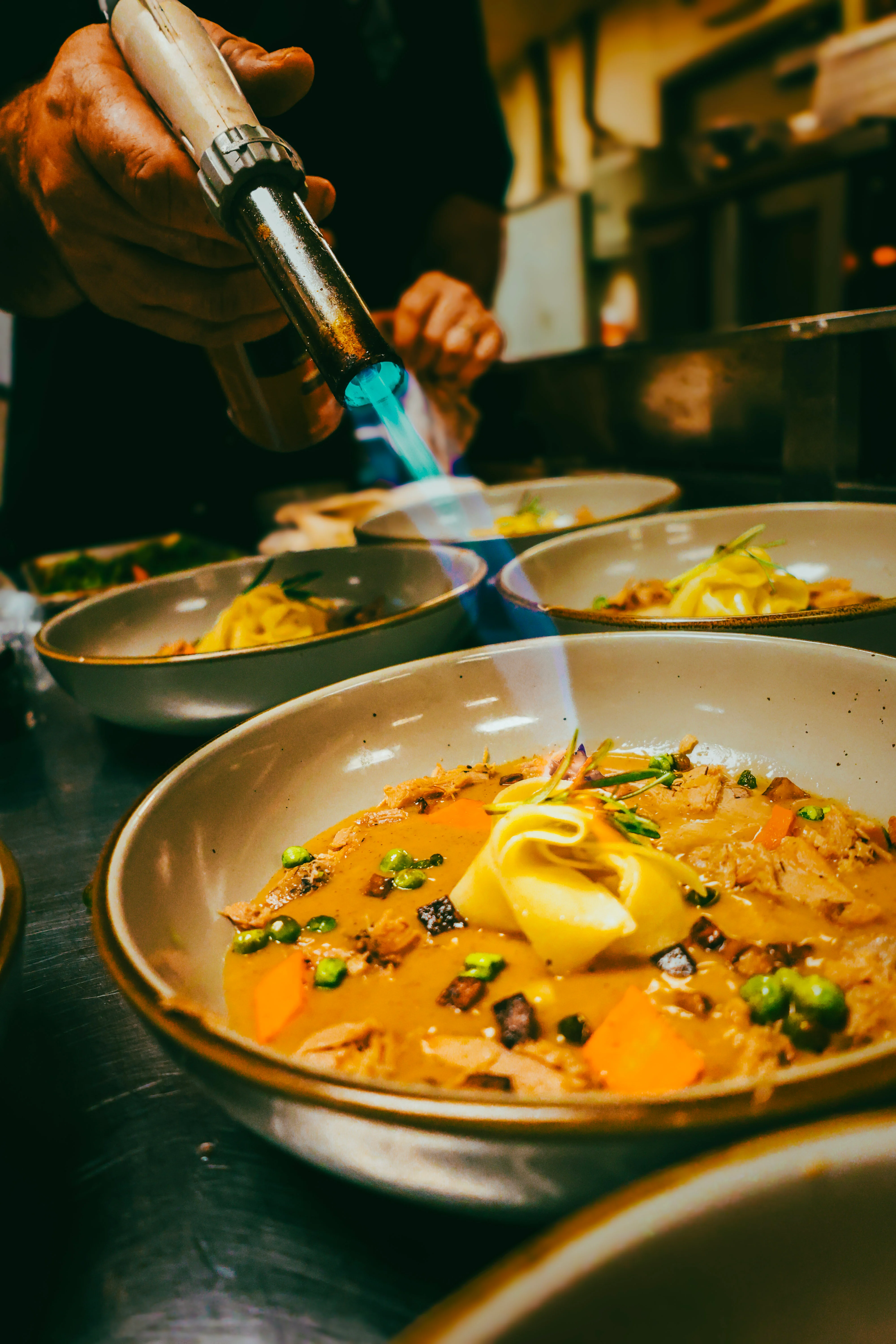 Chef using a torch on Asian-style ramen bowl
