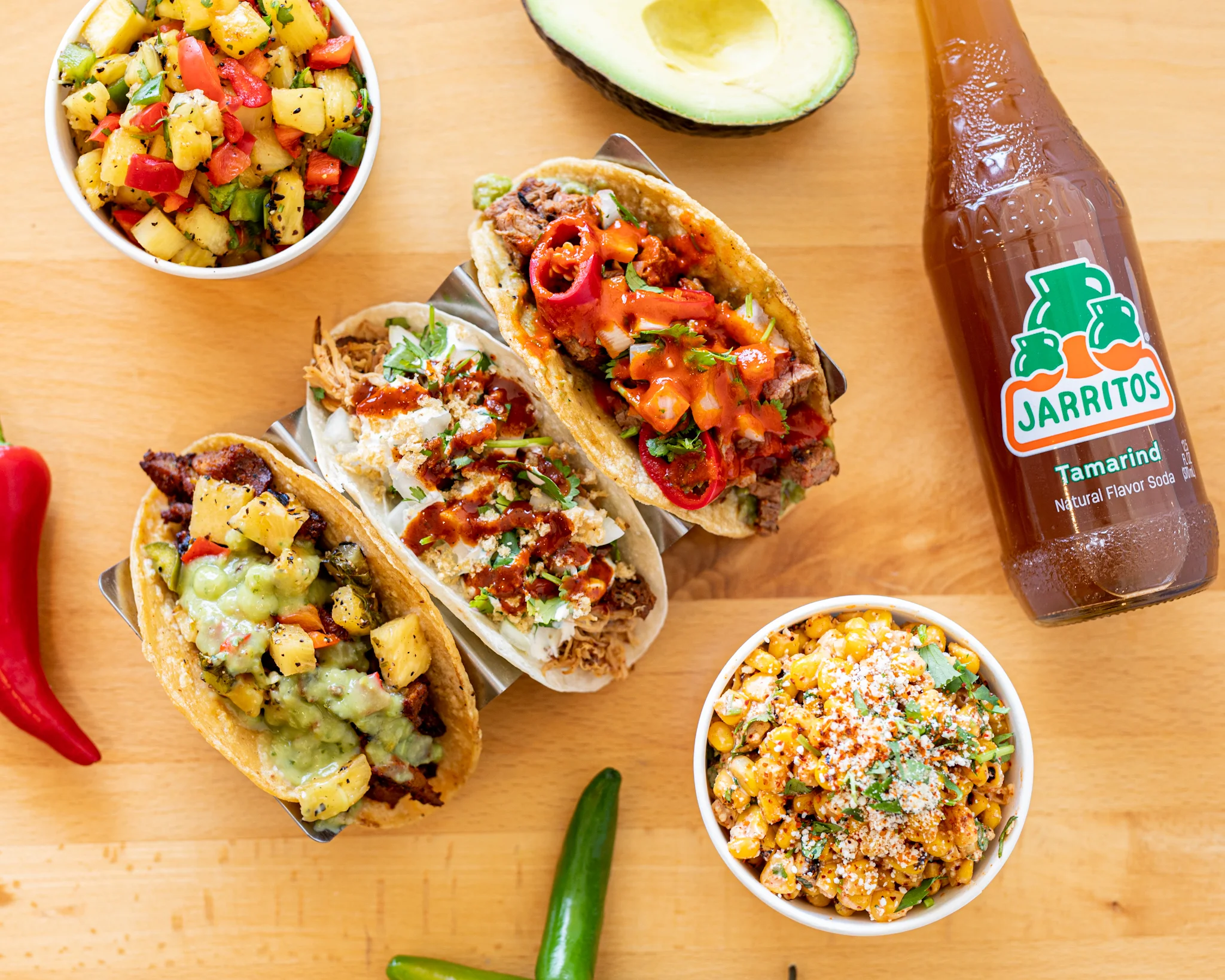 Colorful Mexican street tacos with sides and tamarind soda