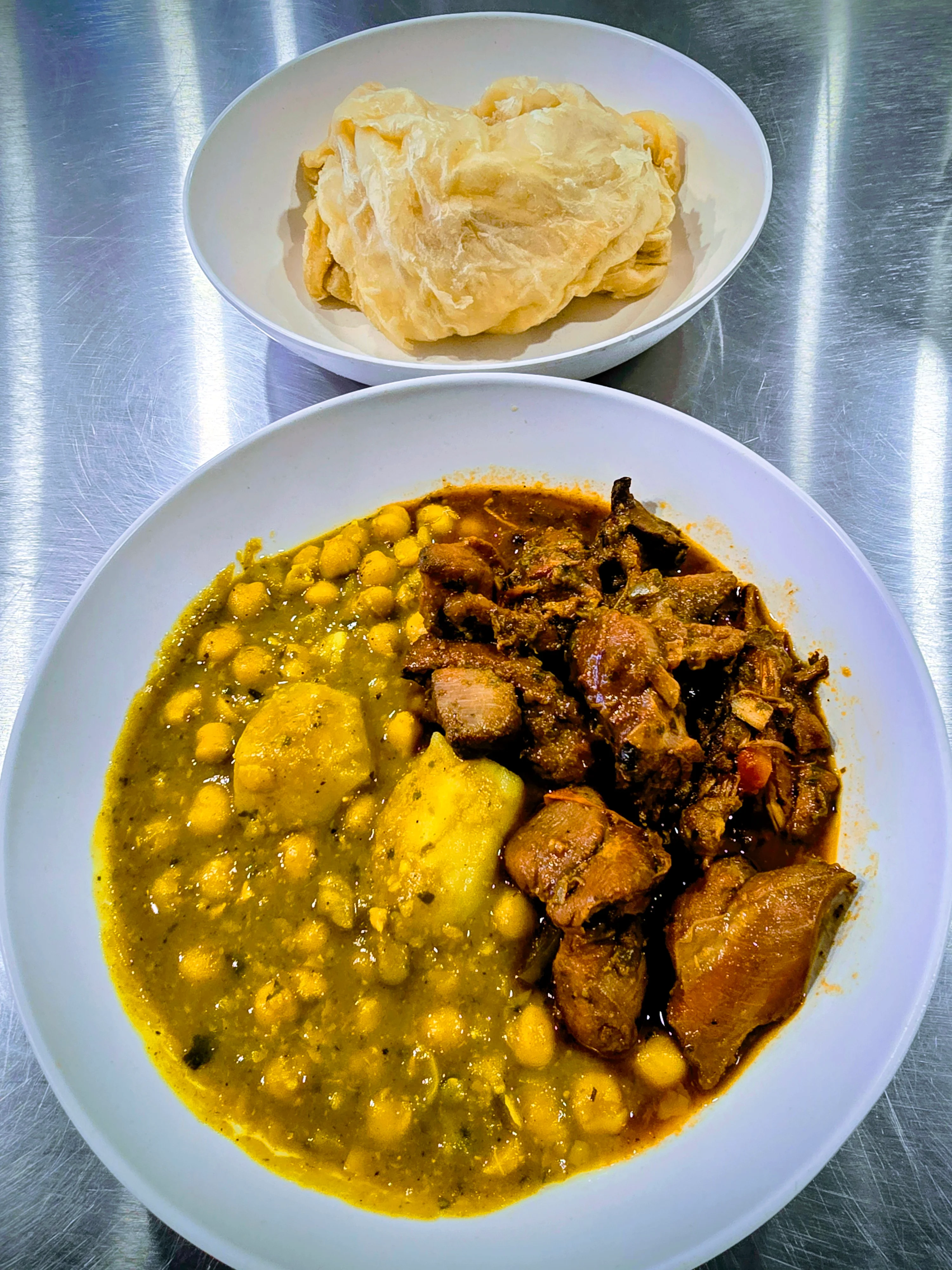 Delicious chicken stew meal served with roti on a plate.
